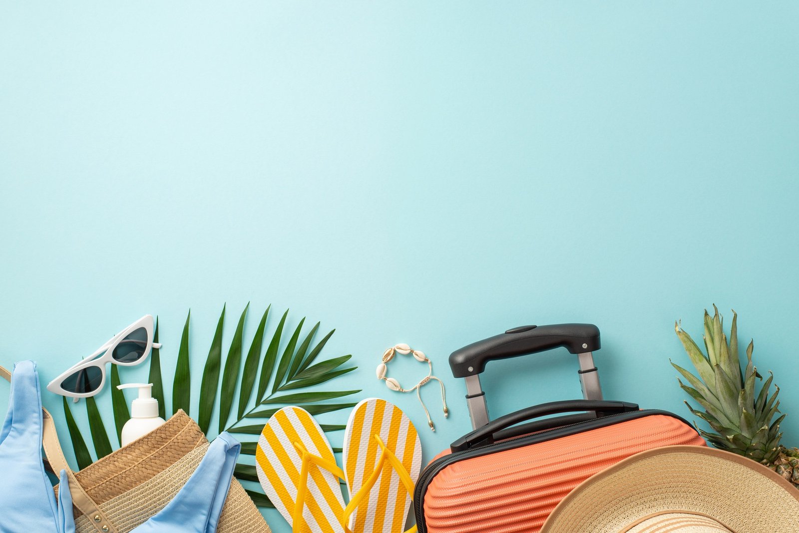 Escape to paradise.Top view showcasing suitcase, beach gear, stylish sunglasses, sunhat