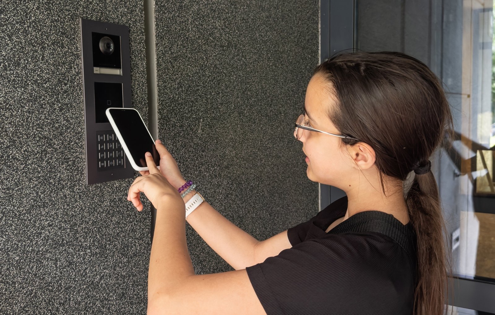 teenage girl using phone scan to digital door lock security systems at home.